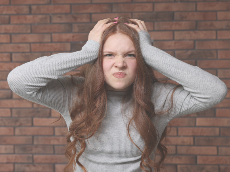 イライラして頭を抱えている女性。顔は怖くて、子供が怯えて寄り付かない位怖い顔している。