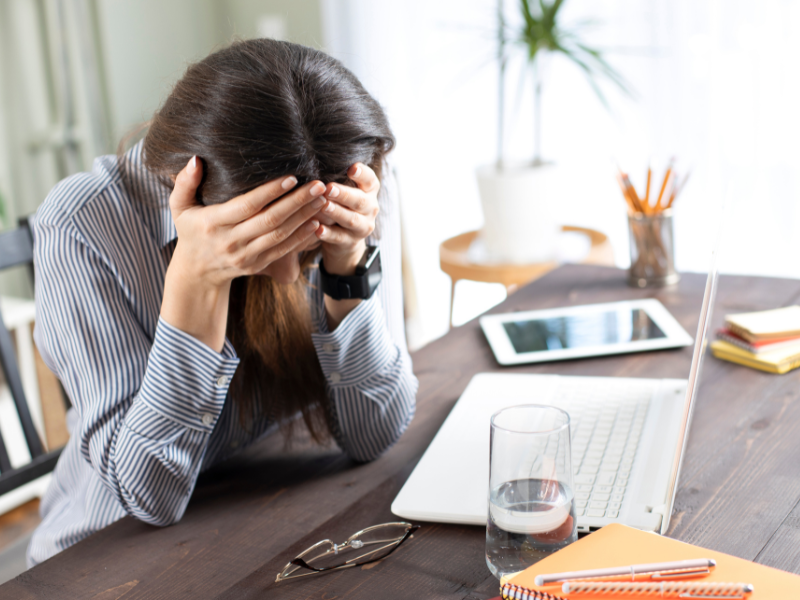 ショックで頭を抱える女性。机の上で、じっとしている