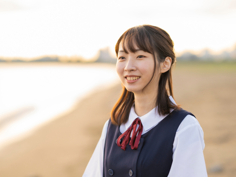 笑顔で海岸に立っている女子生徒が一人