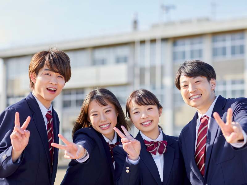 男子高校生二人、女子高校生二人が笑顔でピースをしている